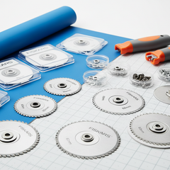 Texto alternativo (alt text) en español:Repuestos para cortadoras circular de telas FISKARS sobre mesa azul